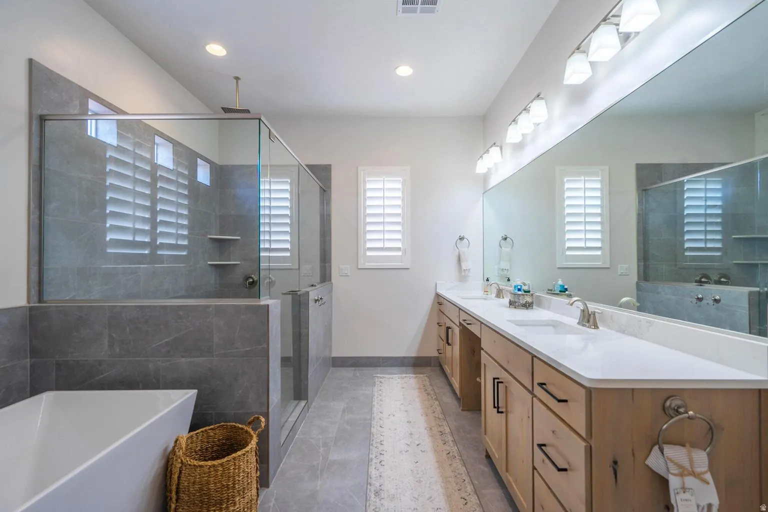 Dual vanity with white undermount sinks, light-toned wood cabinetry, and a full-width mirror