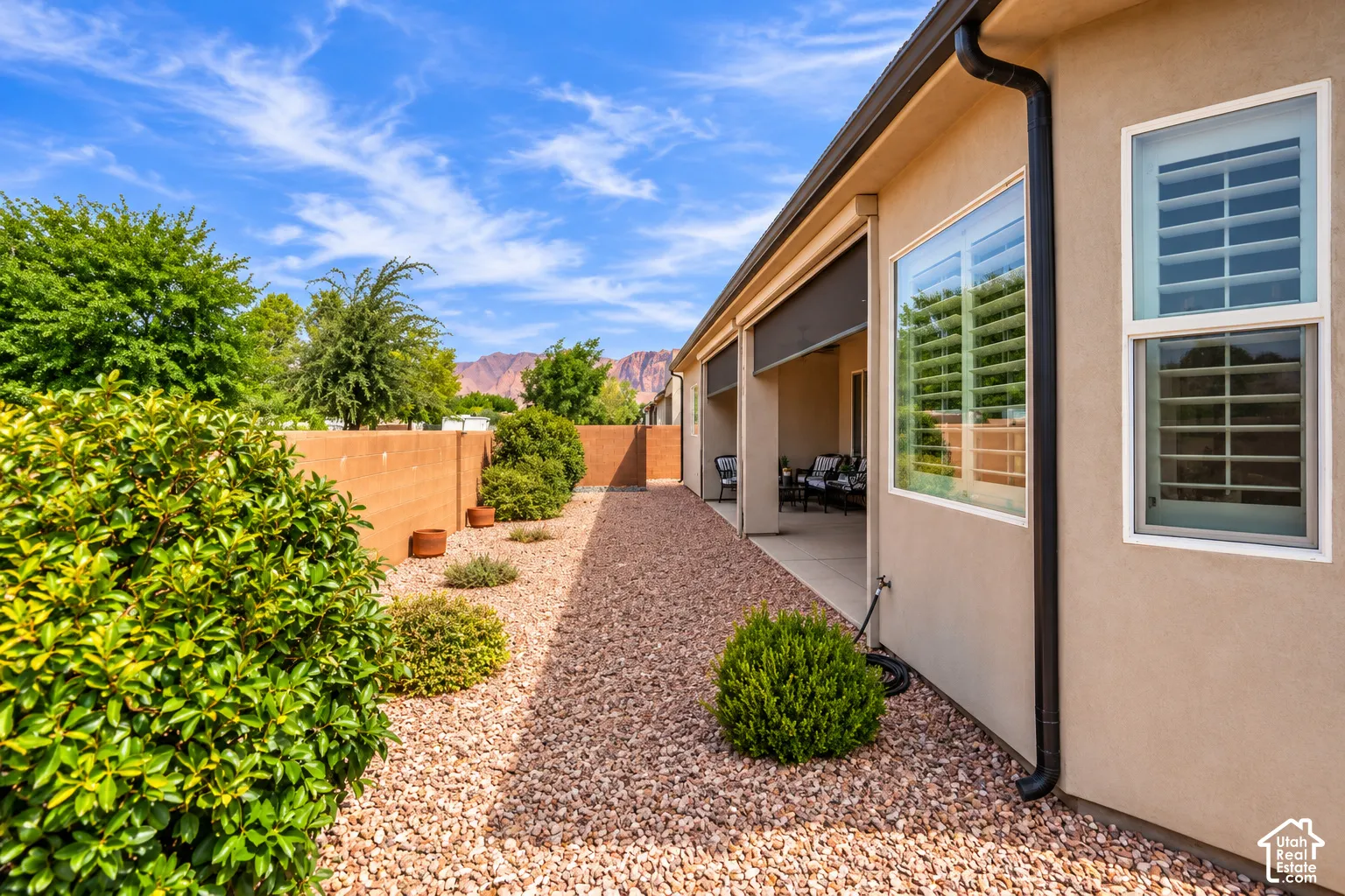 Stucco exterior with white-framed windows, plantation shutters, and a covered patio