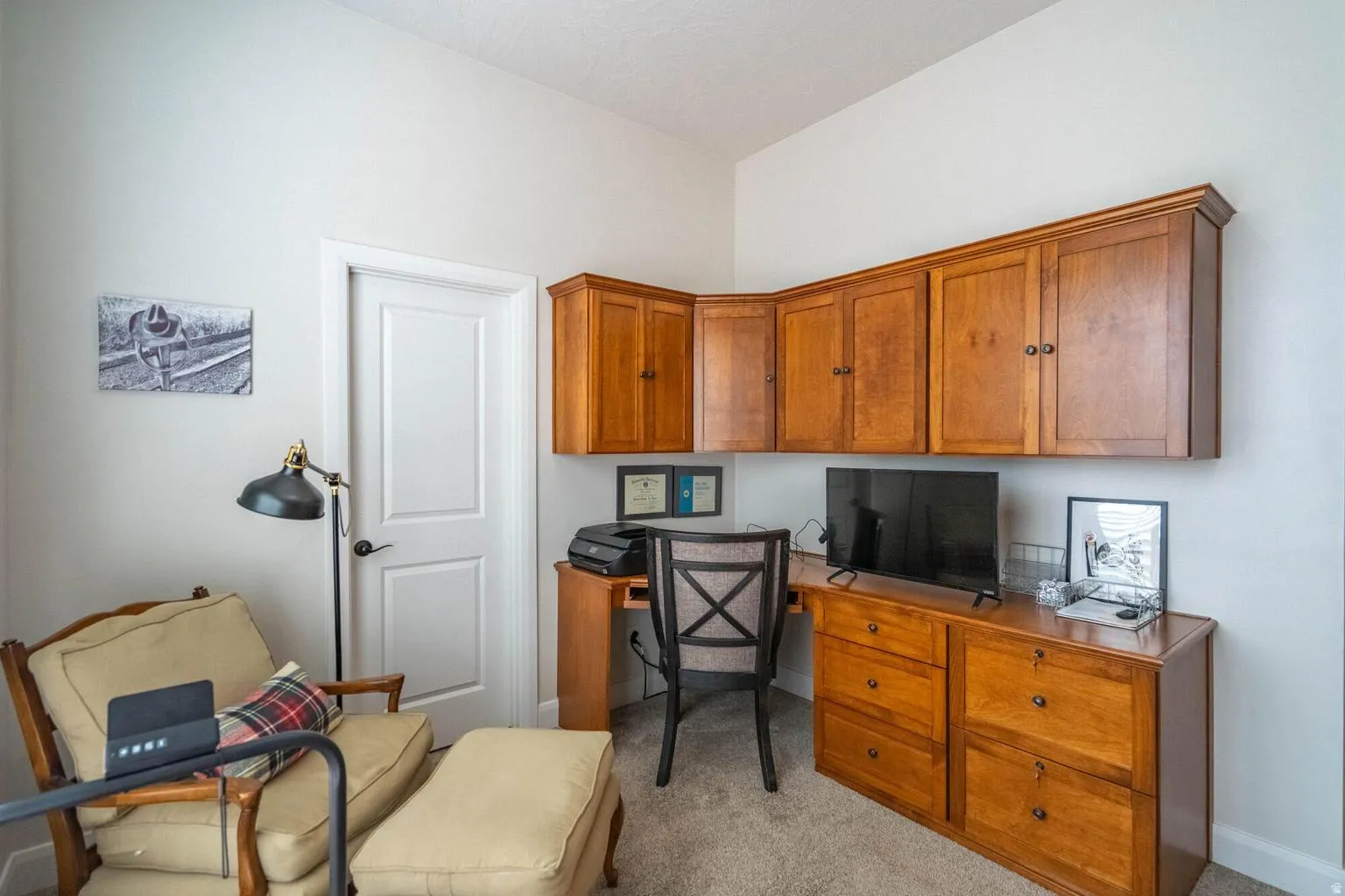 Built-in wood-finish cabinetry and desk unit, white interior door, and light-toned carpet flooring