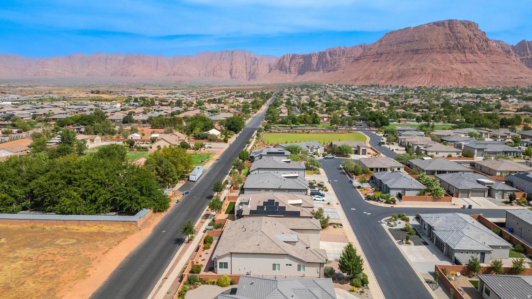 Expansive neighborhood with diverse architectural styles, mature landscaping, paved streets, and mountainous backdrop