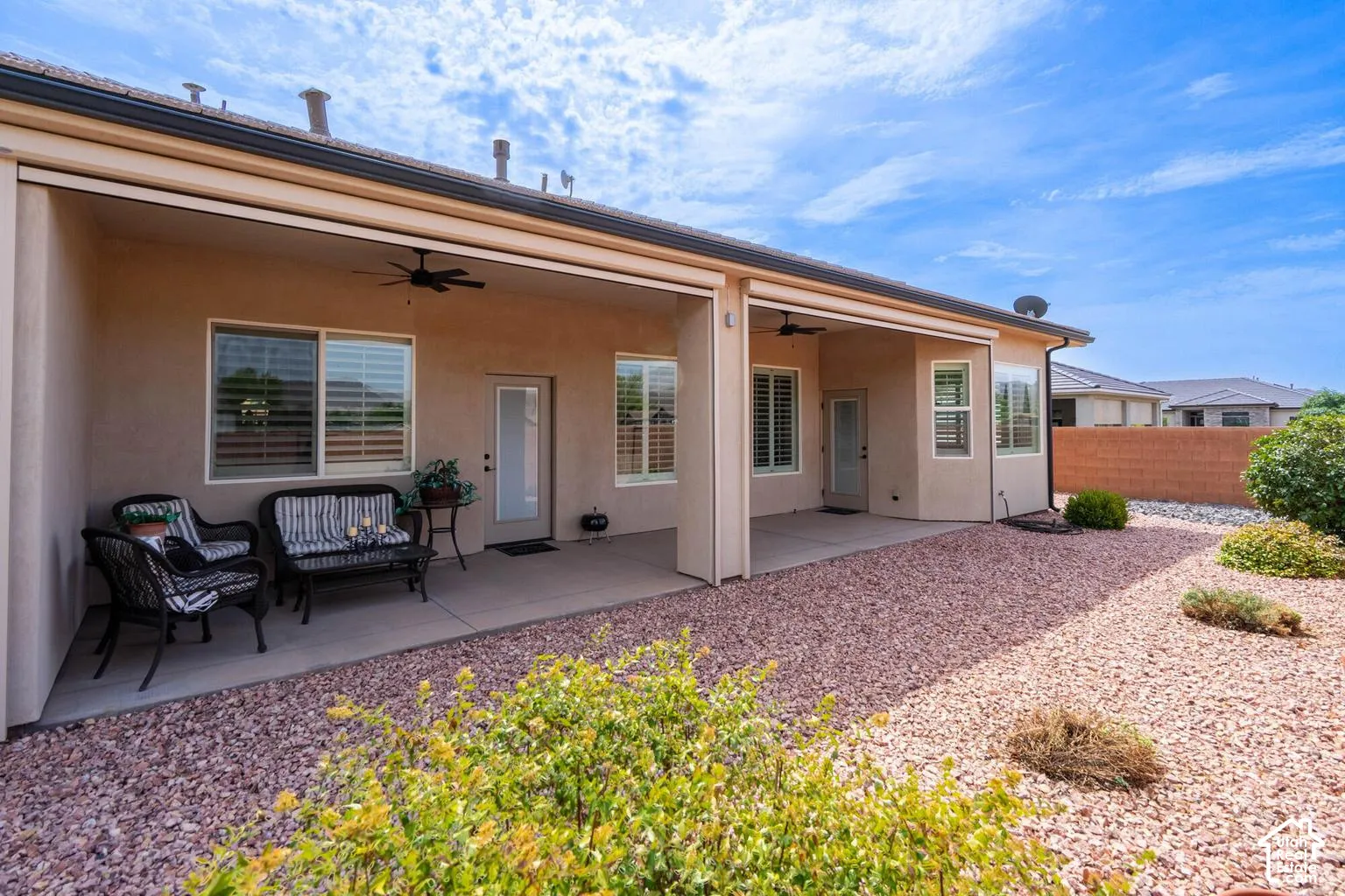 Covered patio with concrete flooring, multiple windows featuring plantation shutters, and ceiling fans