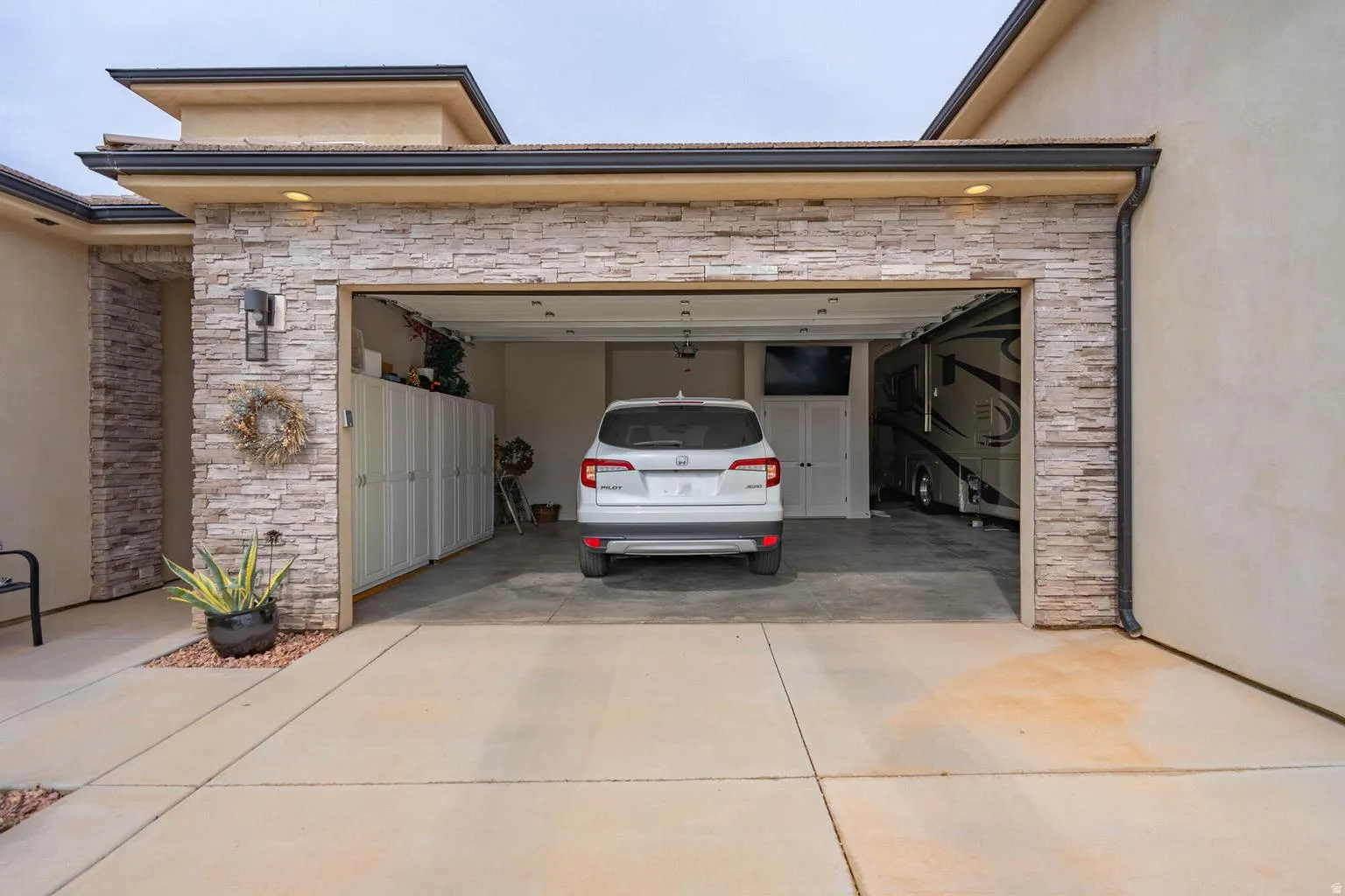 Garage featuring stone-accented facade, recessed lighting, and built-in storage
