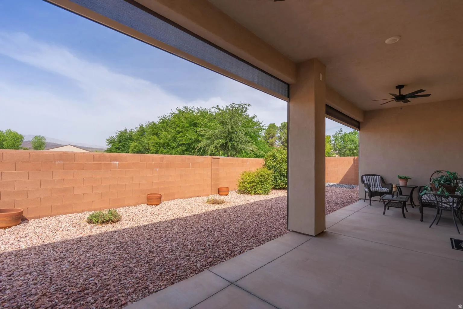 Covered patio featuring a ceiling fan, recessed lighting, concrete flooring, and a privacy wall