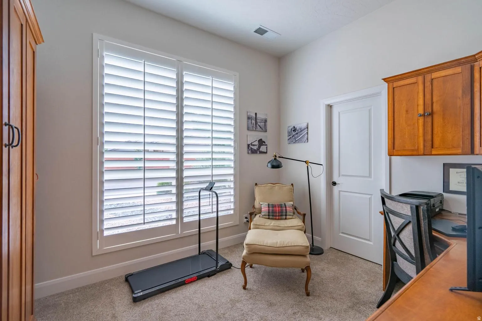 White interior door with black hardware, wood-finish cabinetry, and neutral-toned carpeting