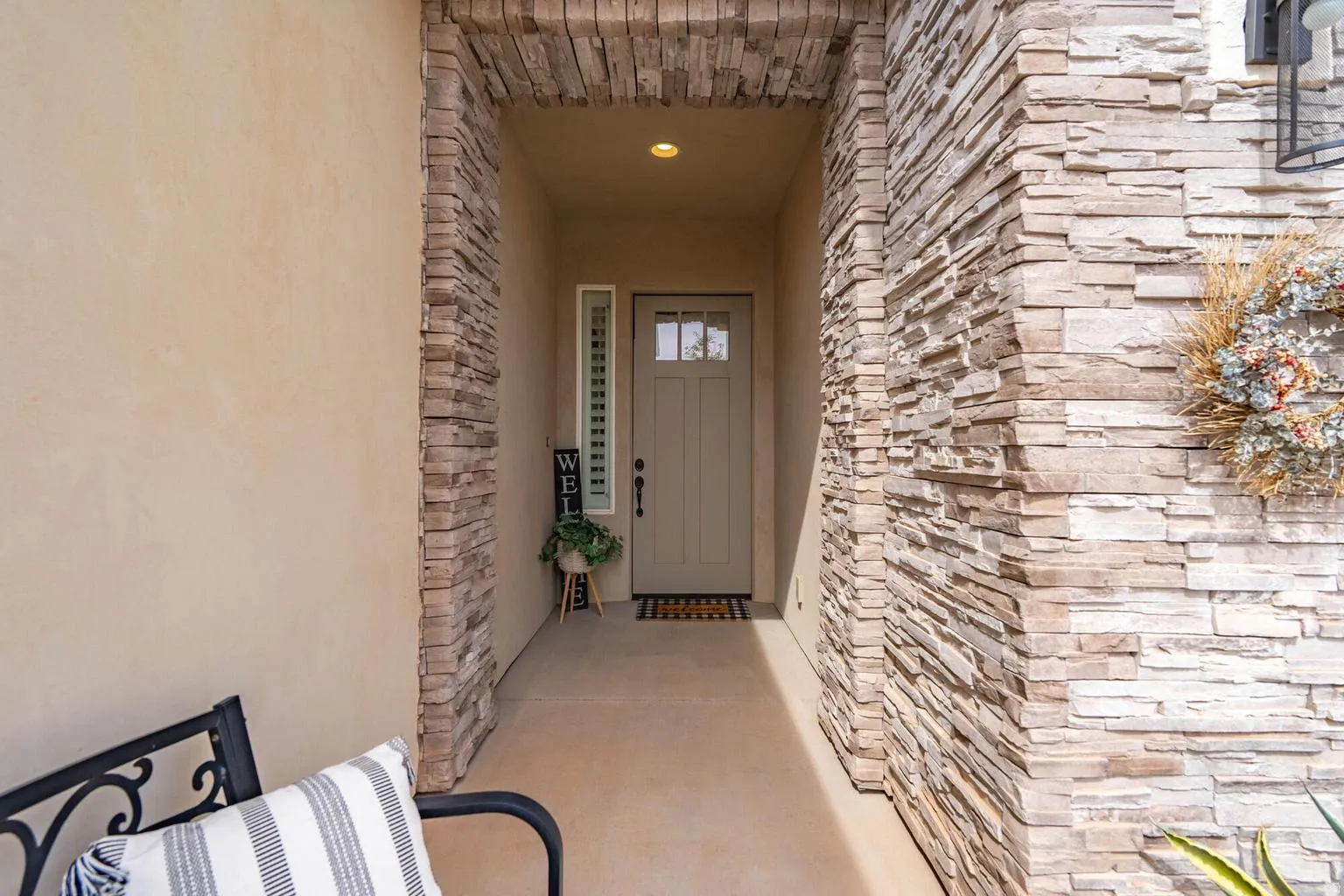 Entryway featuring stacked stone accents, stucco exterior, recessed lighting, and a paneled door with glass inserts