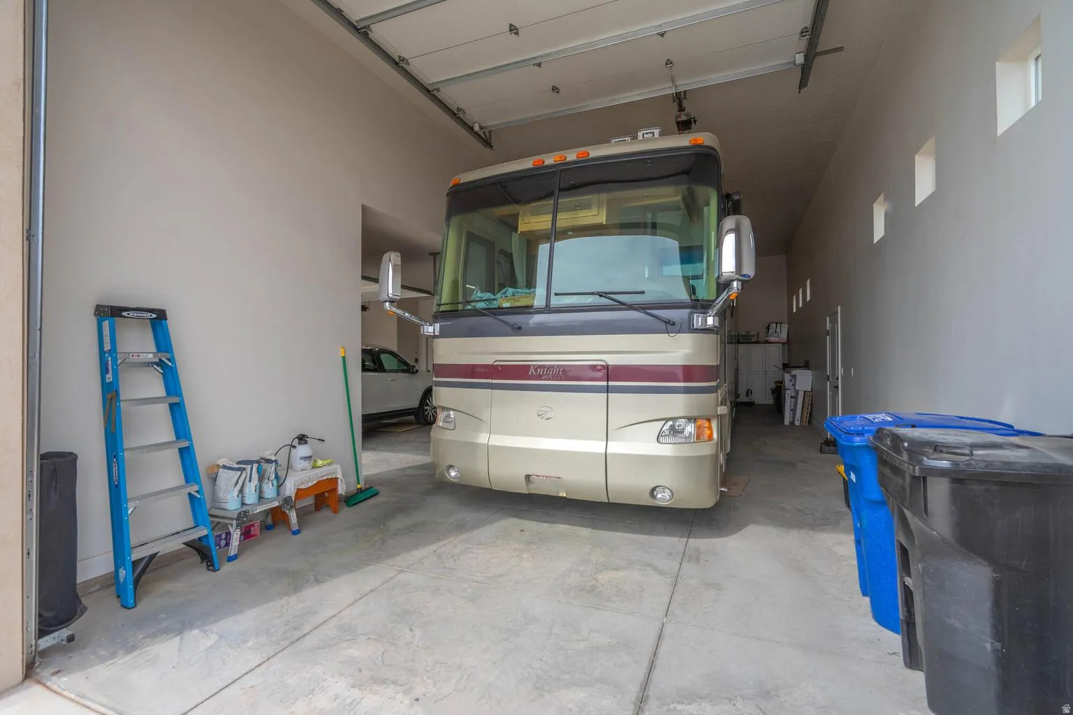 Spacious garage with high ceilings, concrete flooring, and multiple high windows