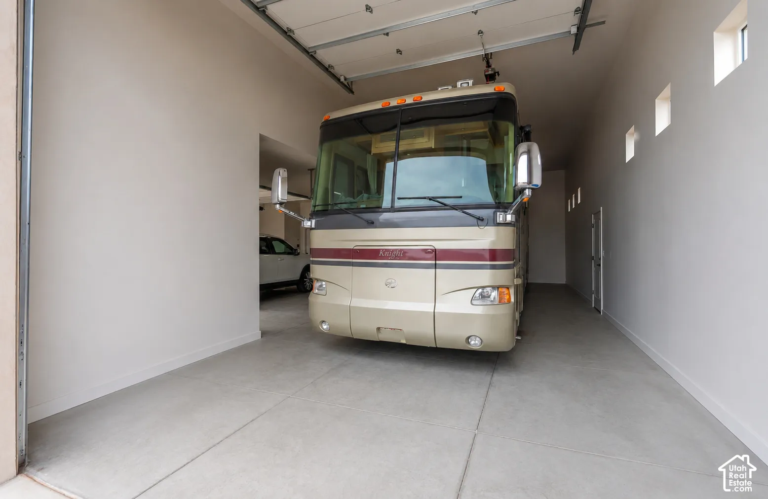 Spacious garage with high ceilings, multiple transom windows, and a dedicated entry door
