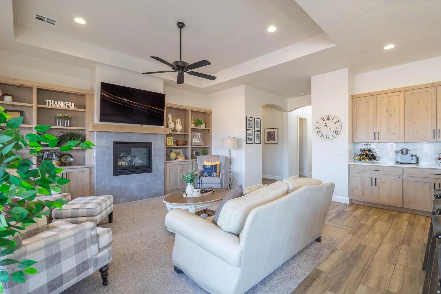Recessed lighting, ceiling fan, built-in shelving, fireplace with stone surround, and wood-finish flooring