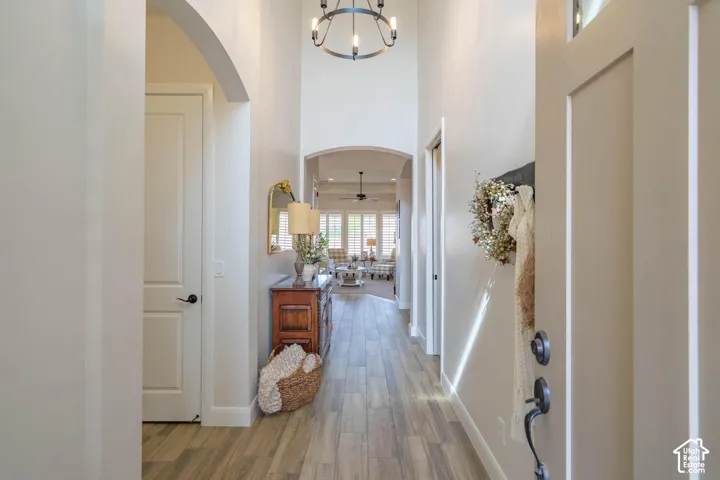 Vaulted entry with wood-finish flooring, arched doorways, and a circular chandelier