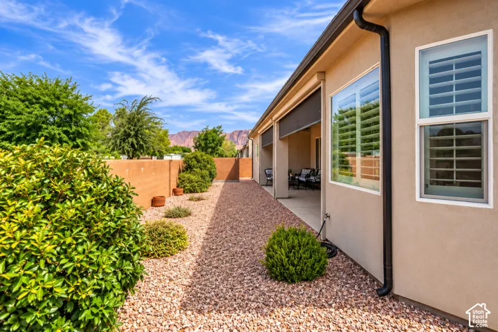 Stucco exterior with white-framed windows, plantation shutters, and a covered patio