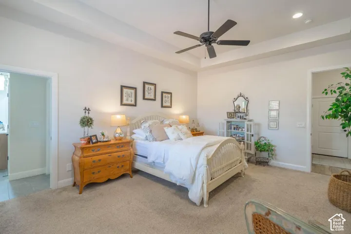 Tray ceiling with recessed lighting, ceiling fan, and carpeted flooring