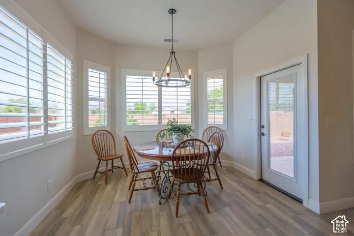 Bay window configuration with multiple windows, plantation shutters, wood-finish flooring, and a glass-paneled exterior door