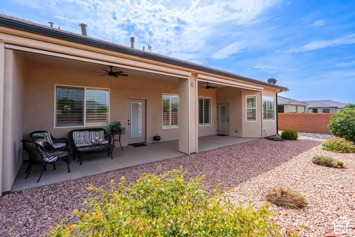 Covered patio with concrete flooring, multiple windows featuring plantation shutters, and ceiling fans