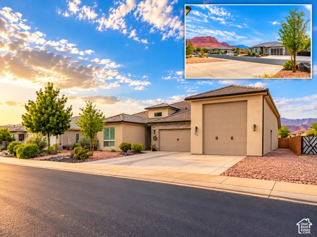 Stucco exterior featuring stone masonry accents, a multi-car garage, and desert-inspired landscaping against a mountain backdrop