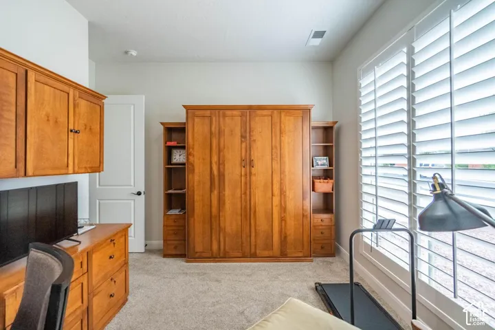 Built-in wood-finish cabinetry, wall-to-wall carpeting, wood-finish shelving, and expansive window with white plantation shutters