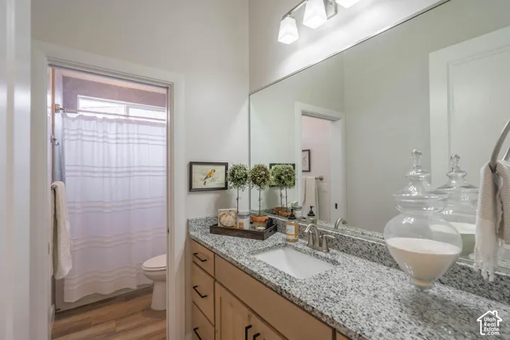Light wood-finish vanity with ample storage, granite countertop, undermount sink, and large wall-mounted mirror