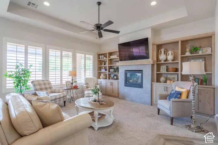 Recessed lighting, ceiling fan, built-in shelving, integrated fireplace, and multiple windows with plantation shutters
