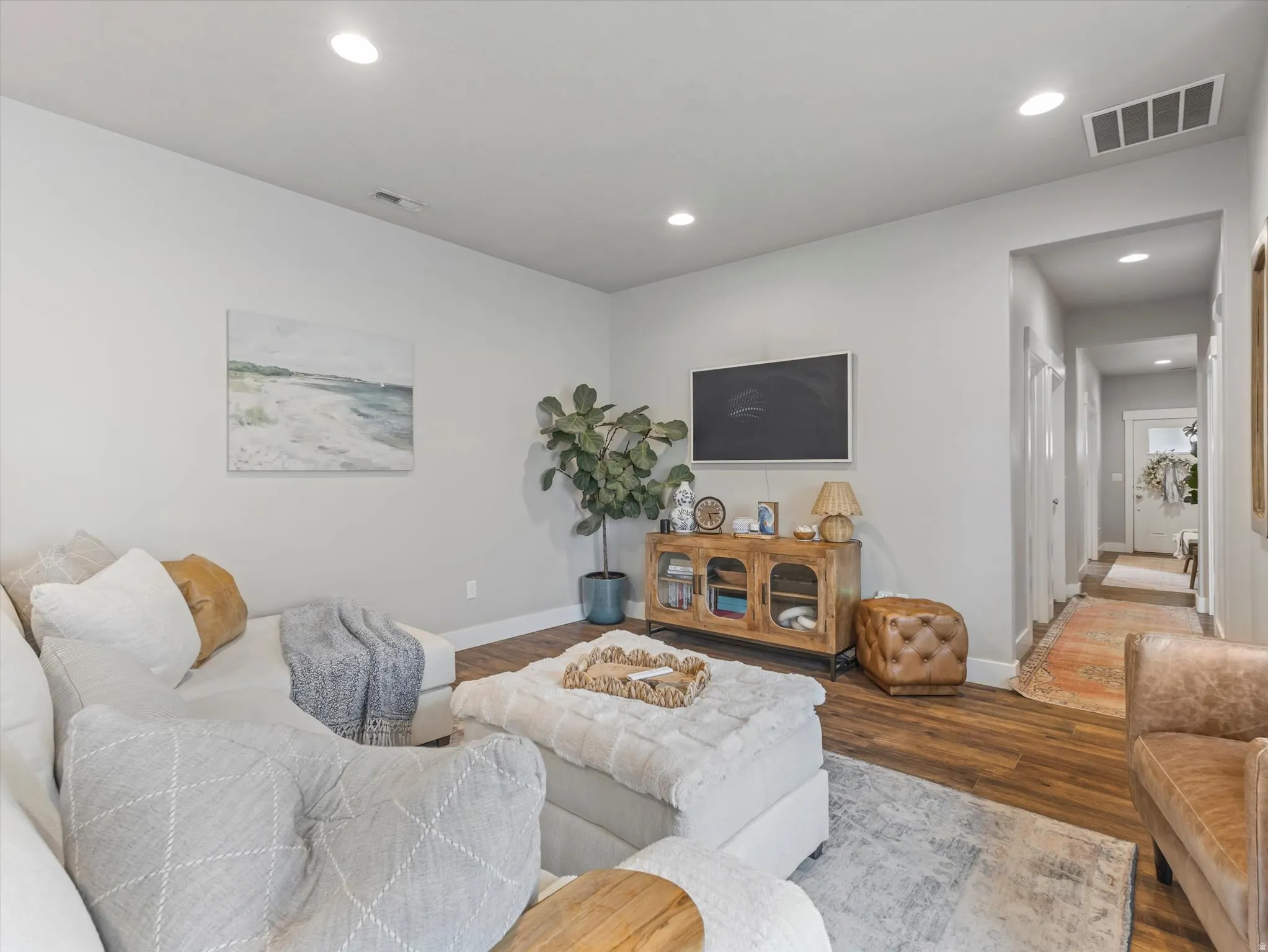 Recessed lighting, wood-finish flooring, light neutral wall tones, and a built-in media console