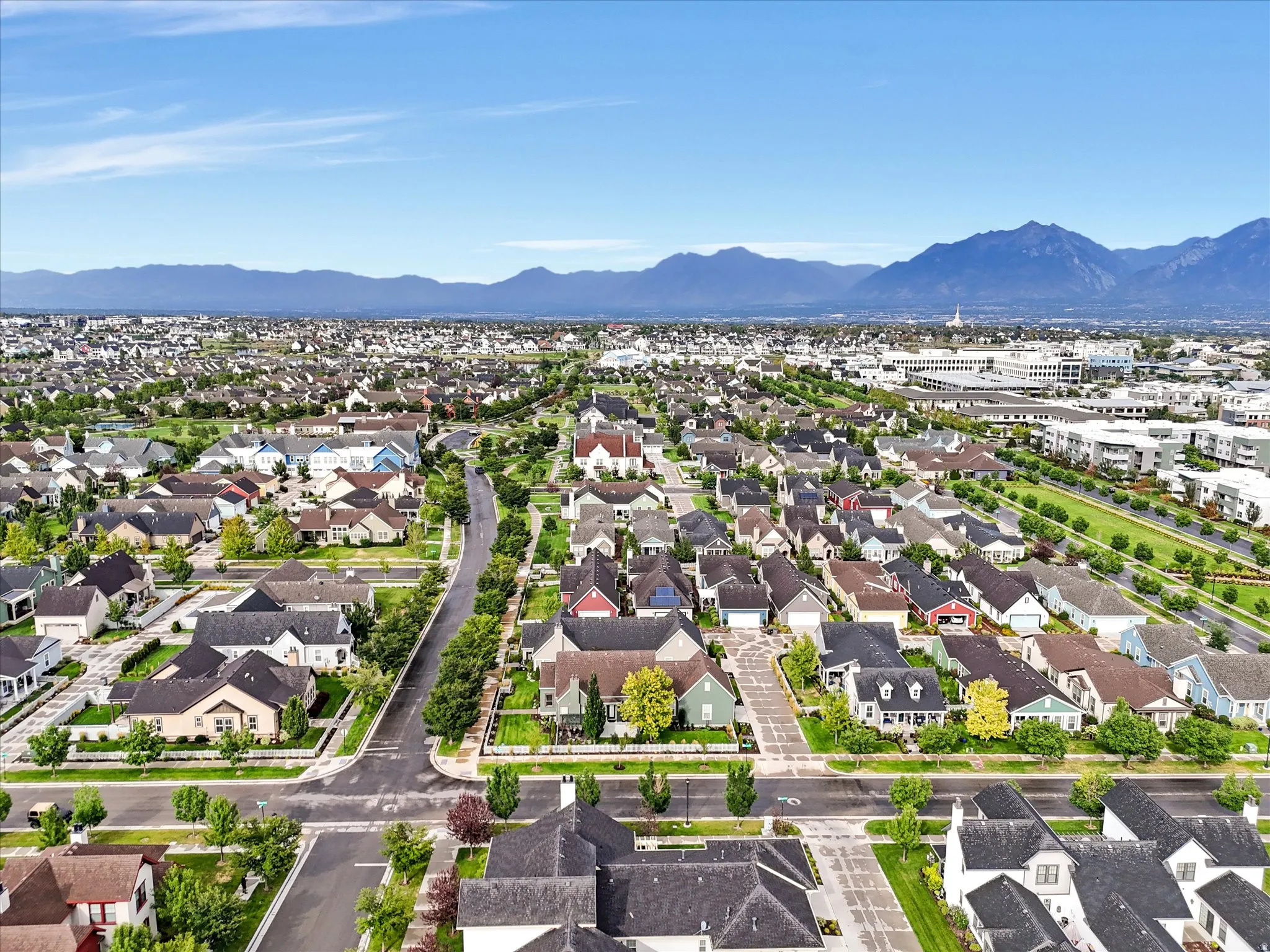 Expansive suburban neighborhood with tree-lined streets, diverse architectural styles, and distant mountain scenery