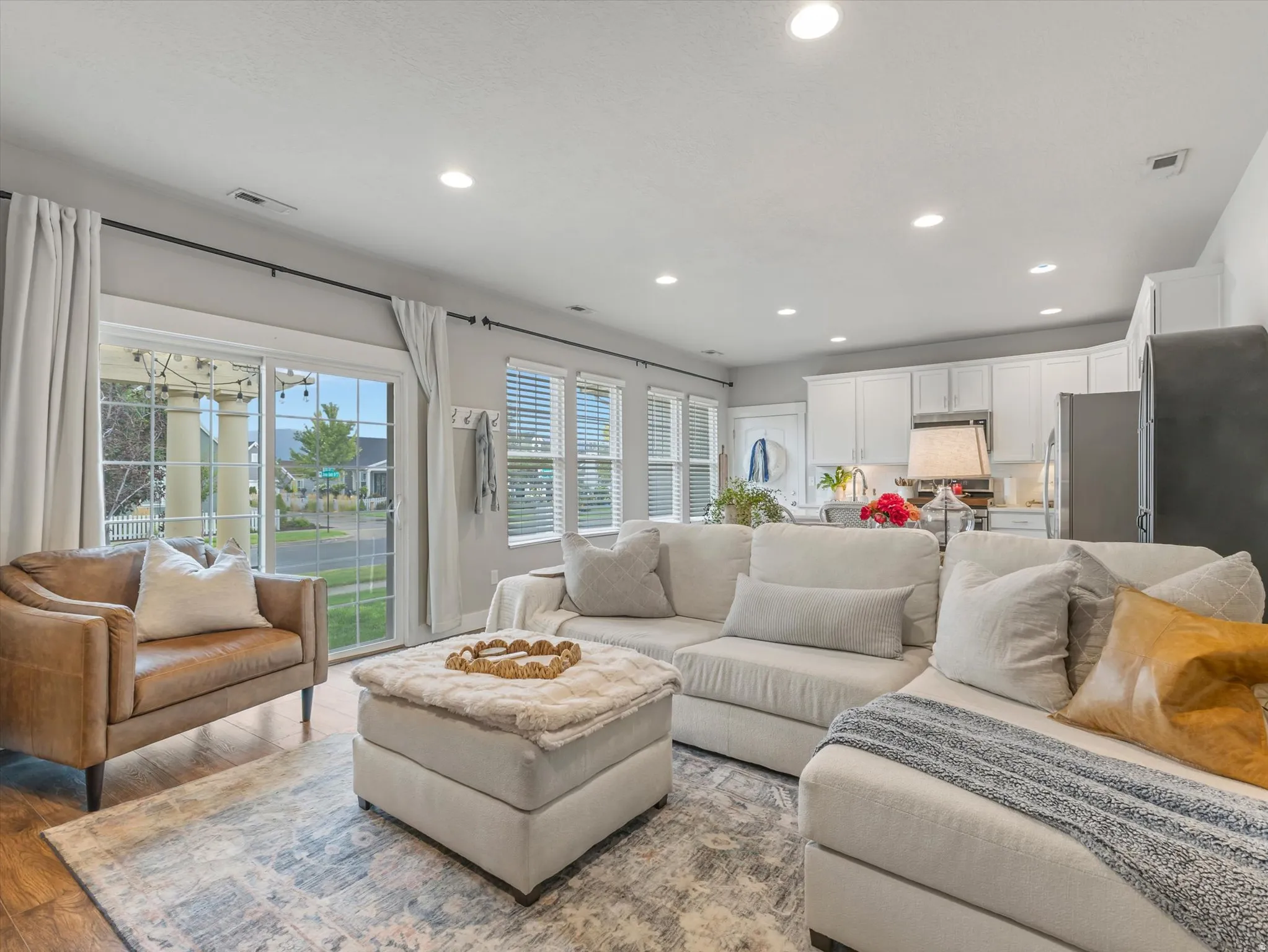 Recessed lighting, wood-finish flooring, white kitchen cabinetry, and a sliding glass door