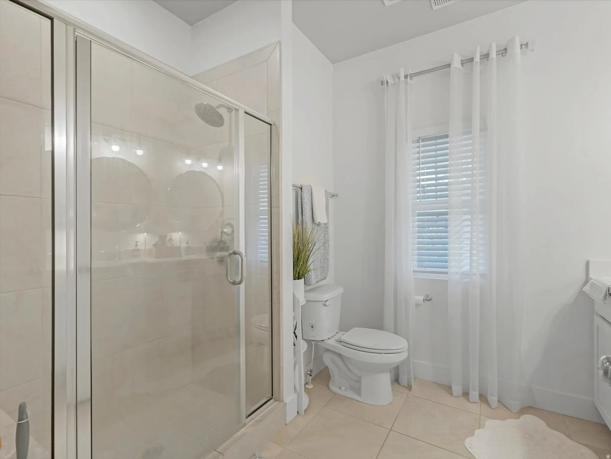 Glass-enclosed shower with a rain showerhead, tiled walls, and a white toilet