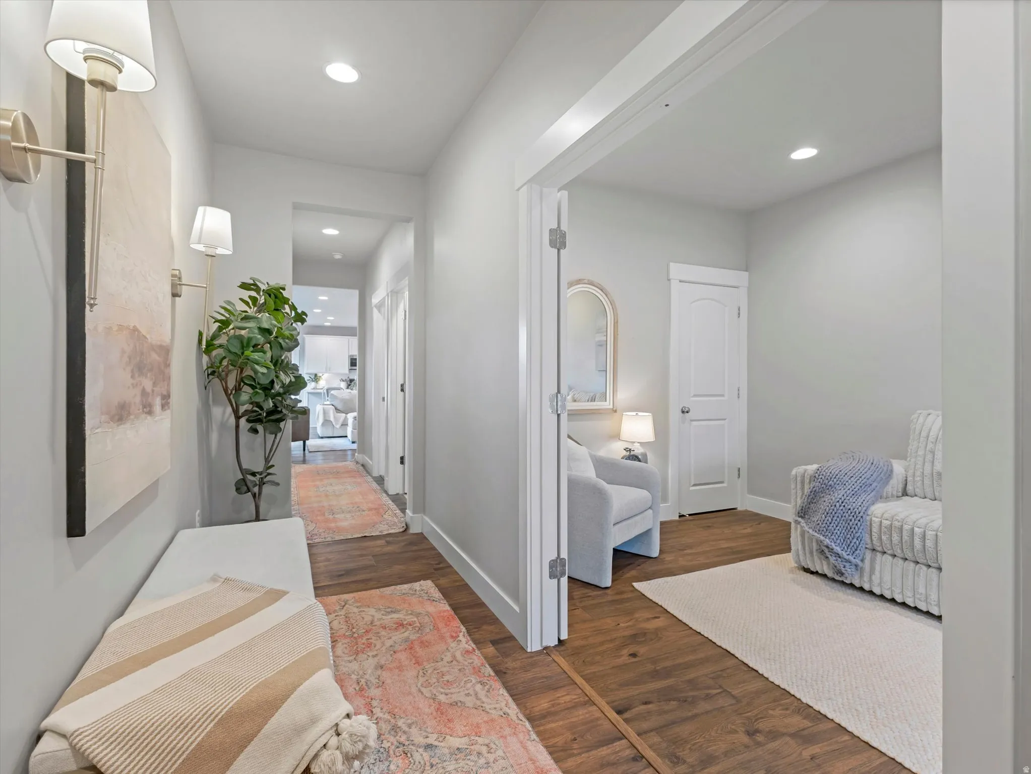 Recessed ceiling lighting, wall-mounted sconces, wood-finish flooring, and crisp white trim