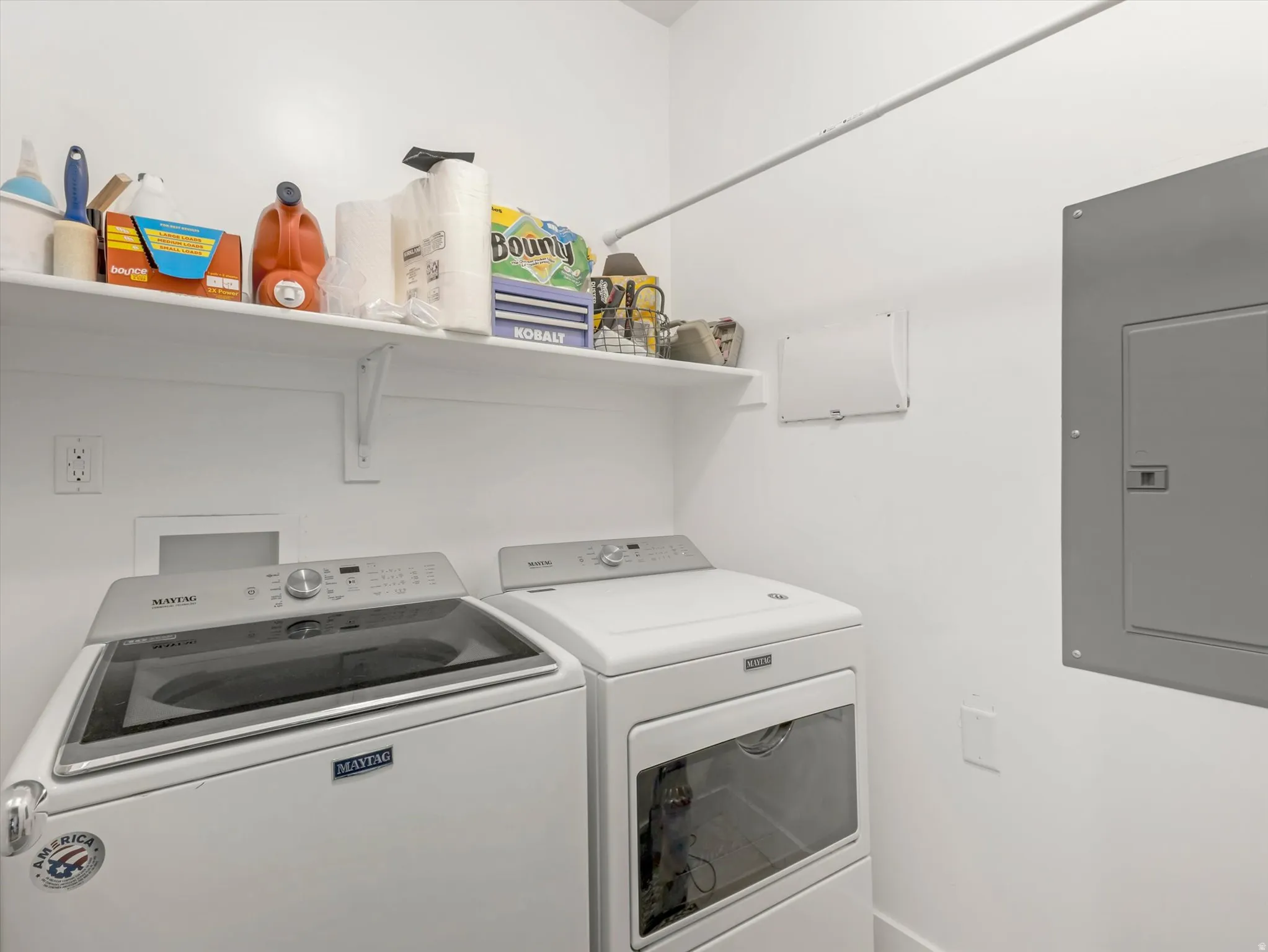 Dedicated laundry area featuring a built-in shelf, appliance hookups, and a white finish