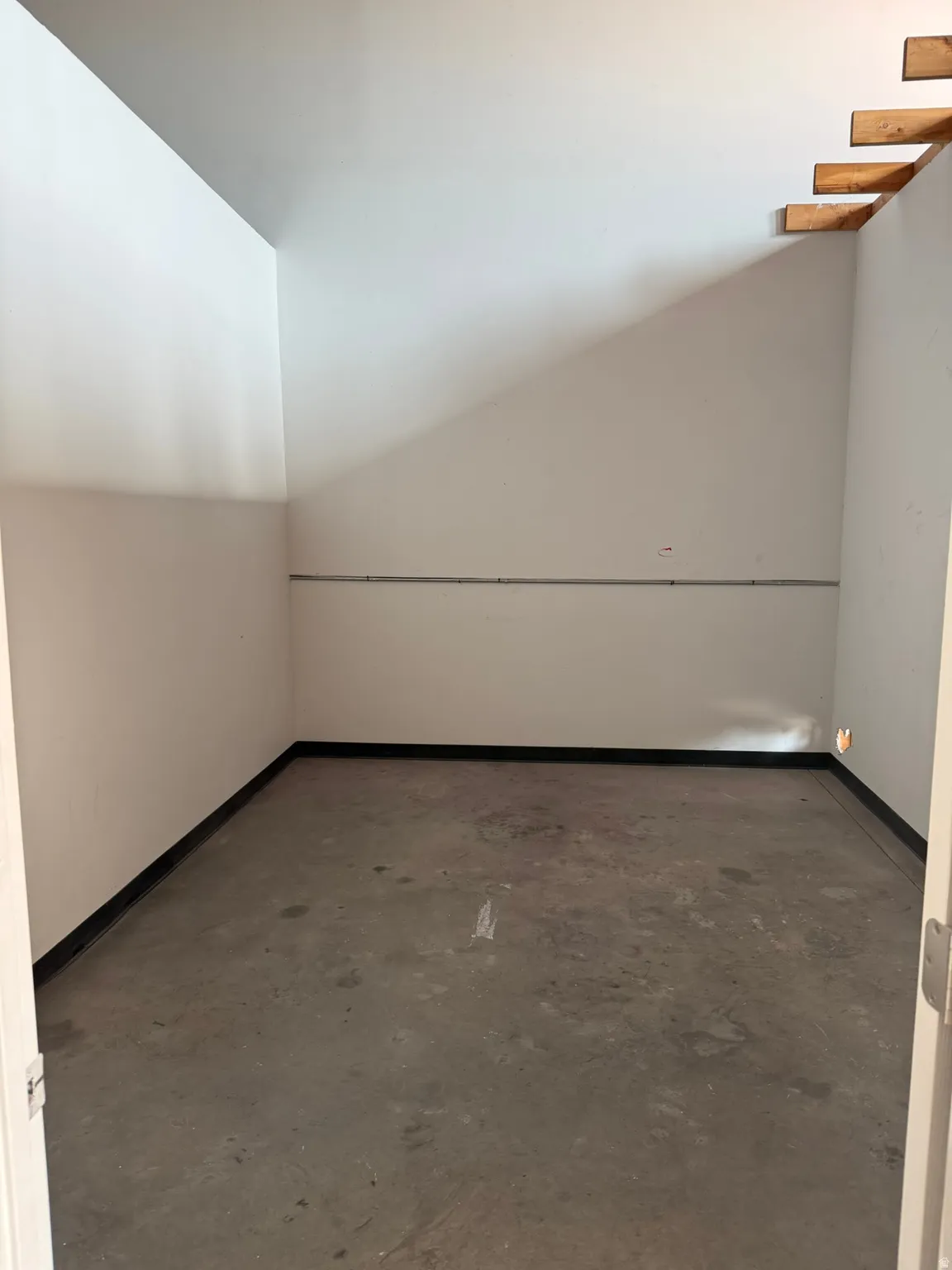 Concrete flooring with white walls and exposed wood framing