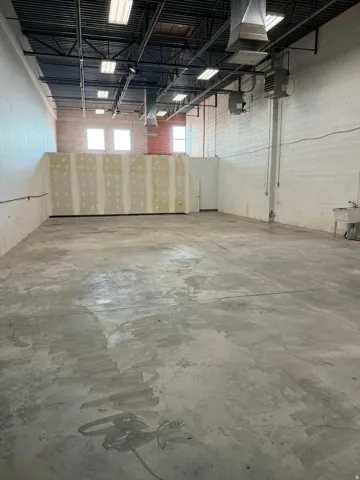 Open floor plan featuring concrete flooring, exposed ceiling with ductwork, multiple windows, and a utility sink