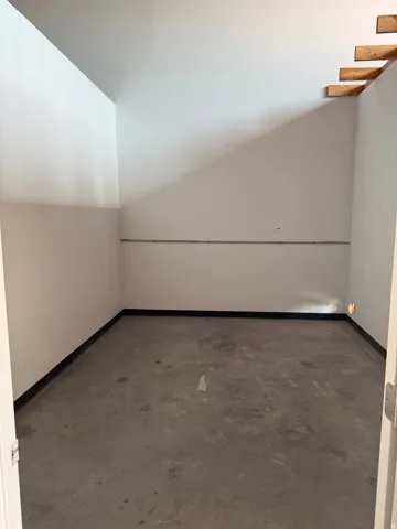 Concrete flooring with white walls and exposed wood framing