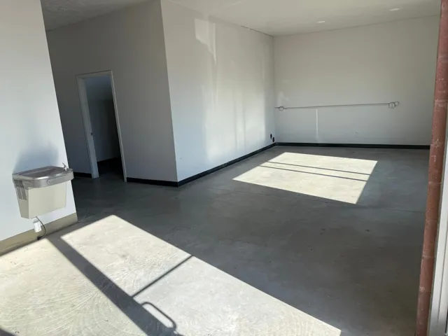 Spacious room with concrete flooring, white walls, and a built-in water cooler