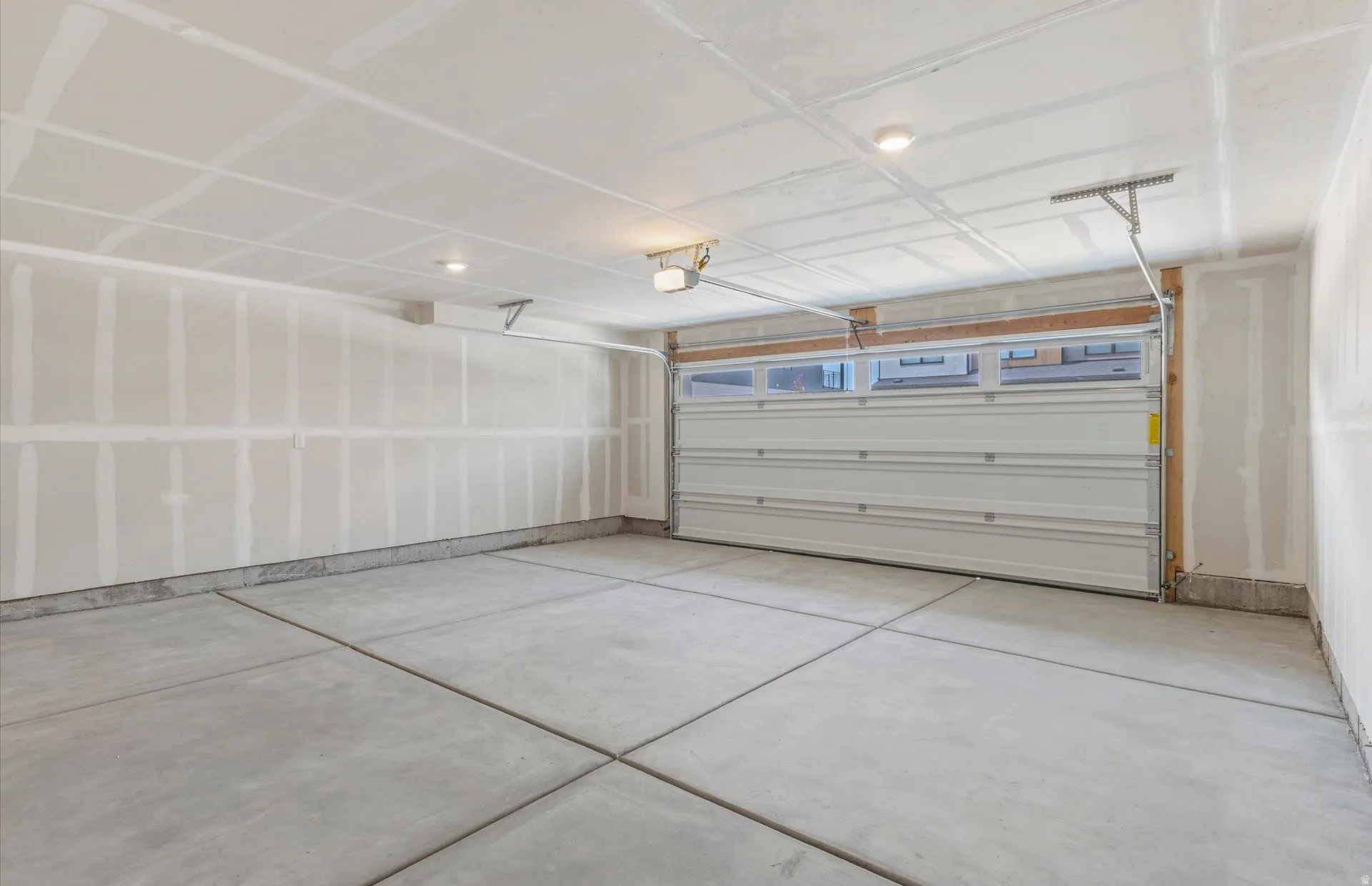 Spacious garage with concrete flooring, automatic garage door, and ample overhead lighting