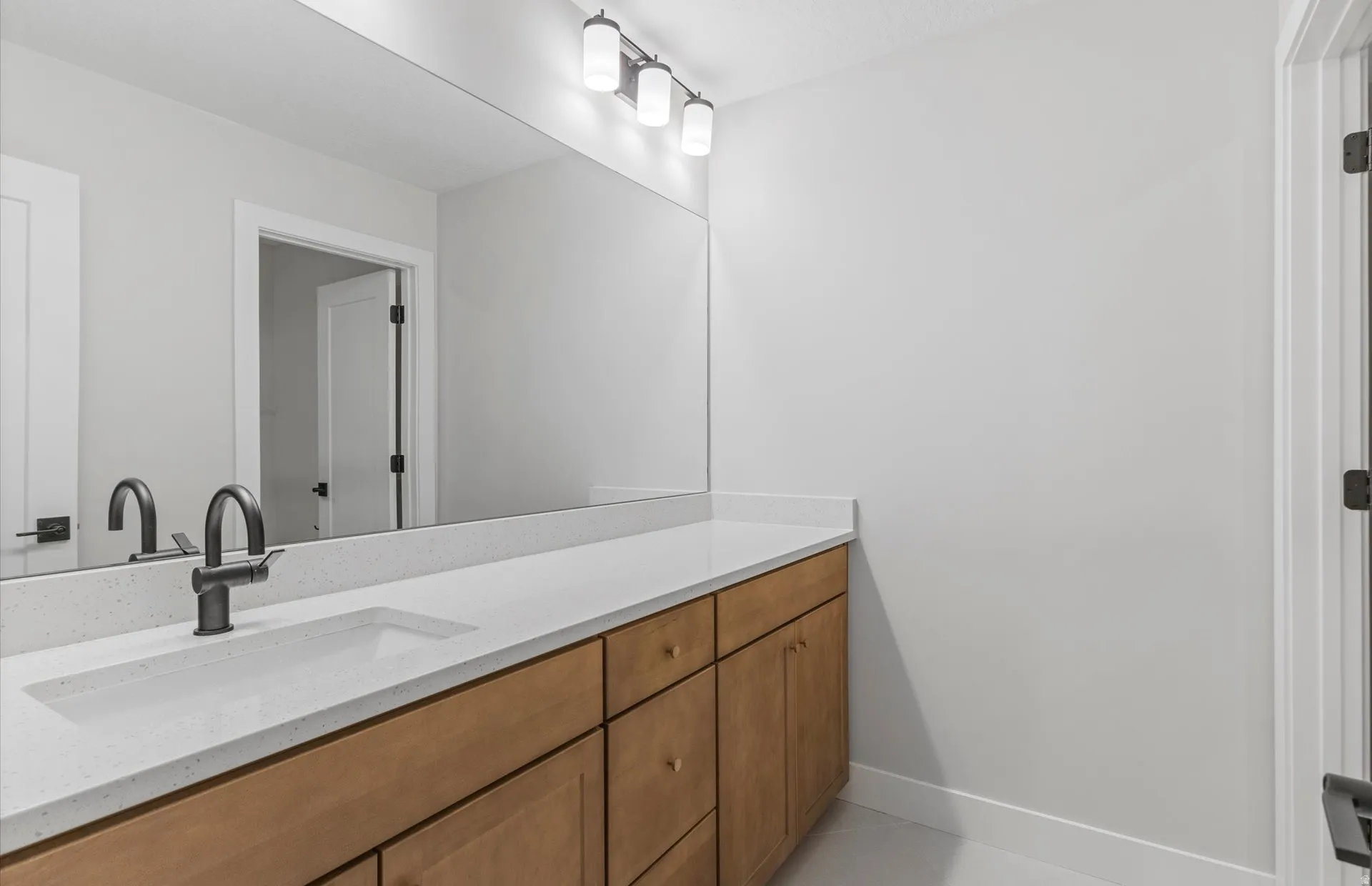 Expansive vanity with light wood-finish cabinetry, a single integrated sink, and a dark bronze-finish faucet