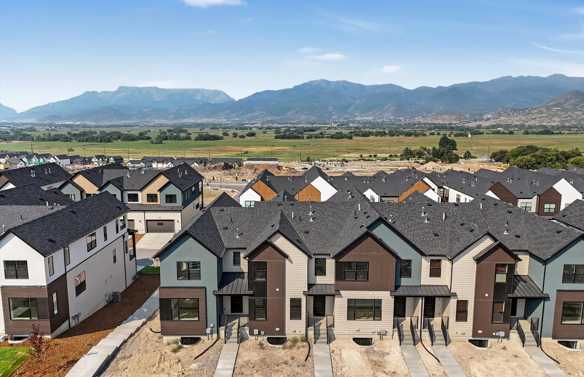 Modern row houses featuring multi-toned exteriors, dark shingle roofing, and mountain scenery