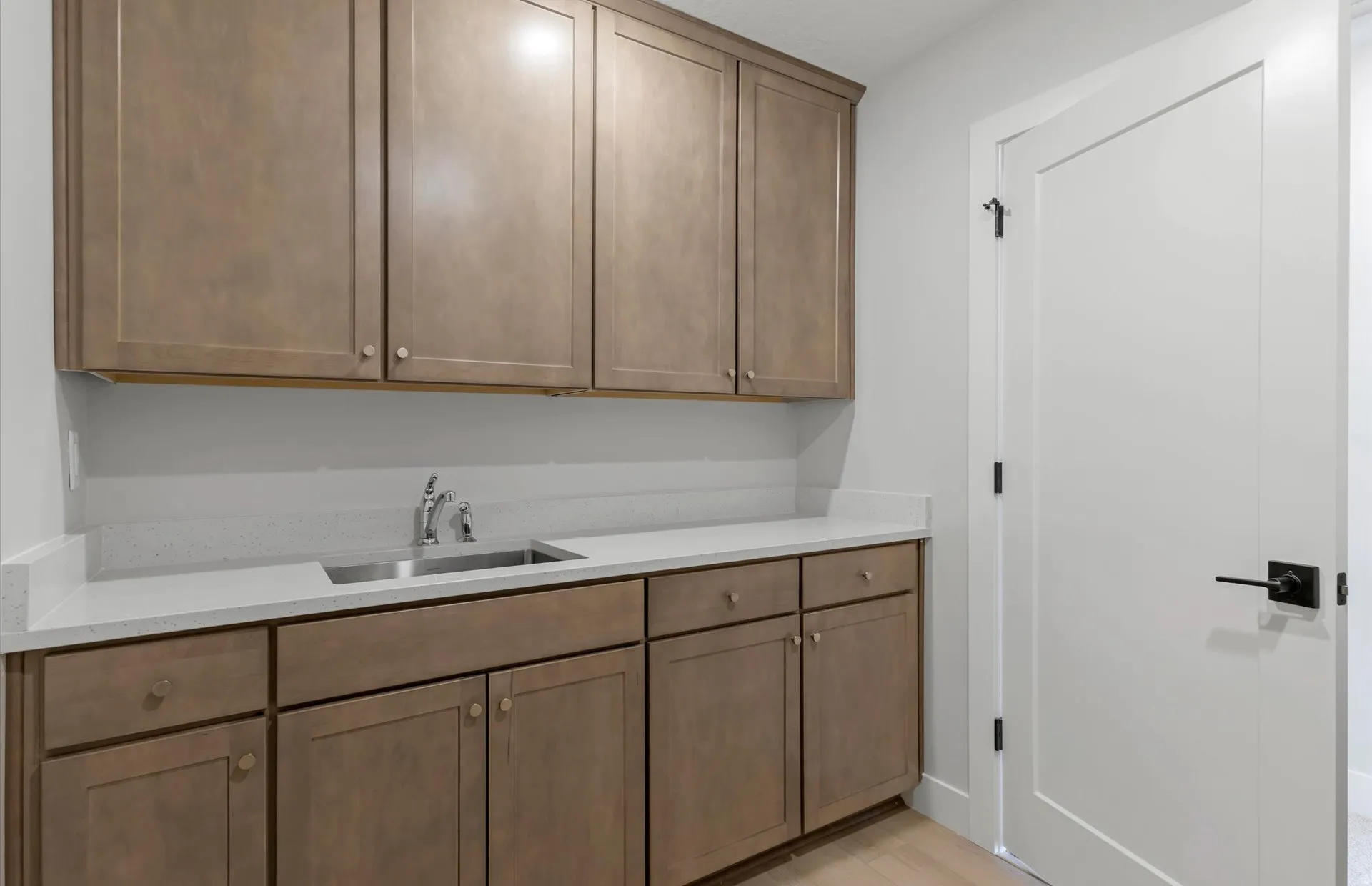 Extensive cabinetry with a wood-finish, light-toned countertop, stainless steel sink, and modern flat-panel door
