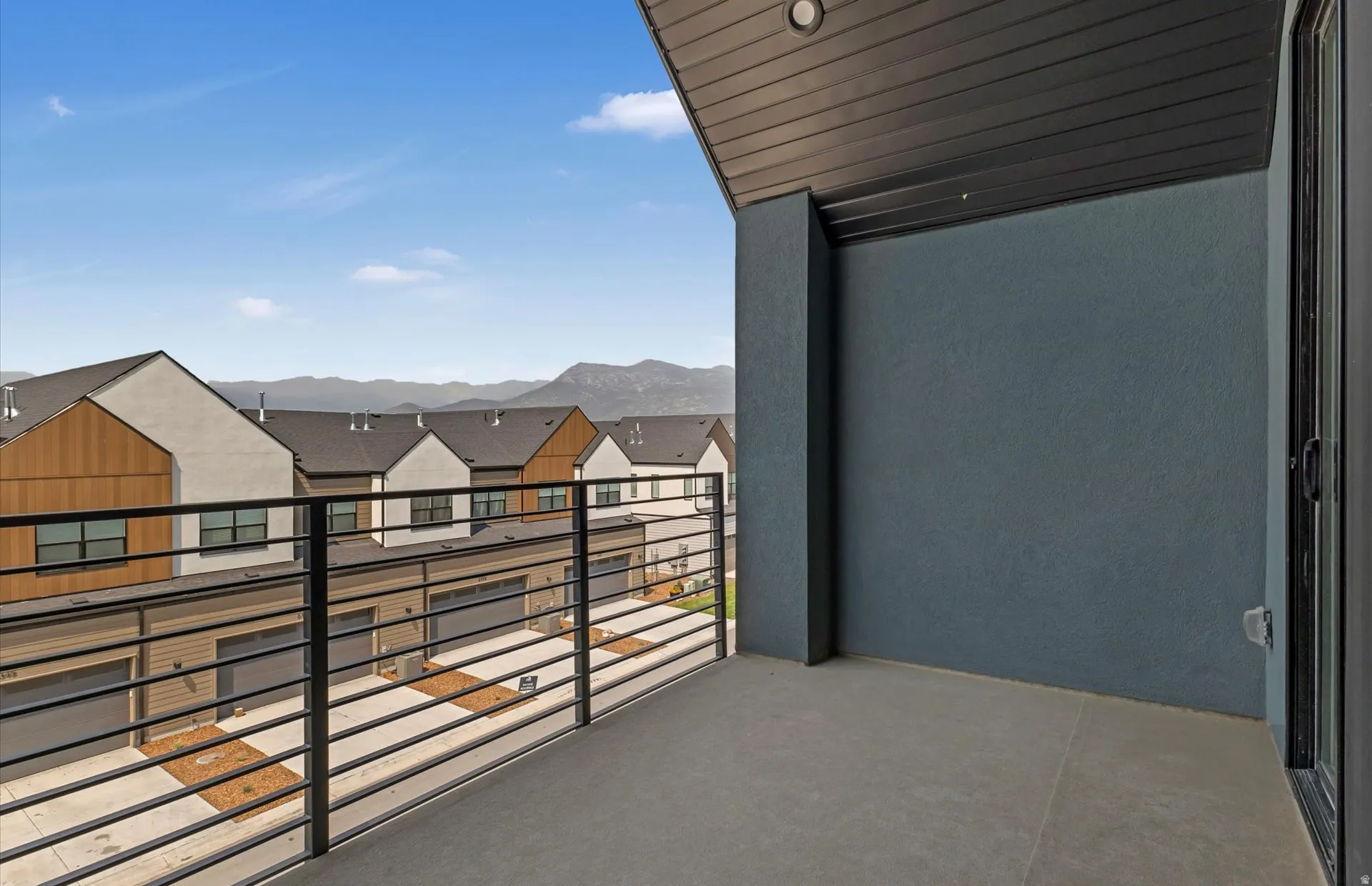 Private balcony with concrete flooring, modern black metal railing, and a sliding glass door