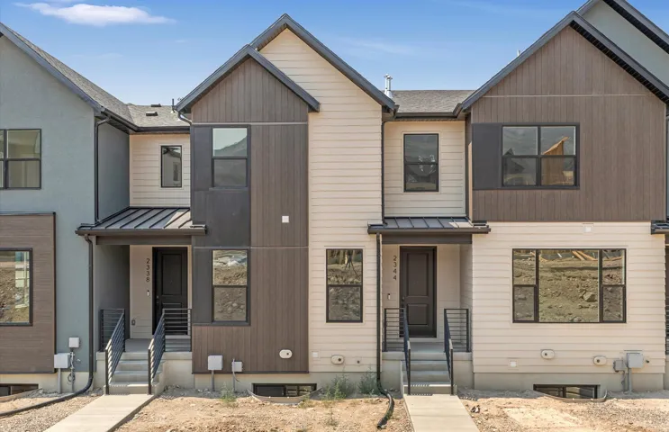 Contemporary townhome exterior featuring multi-toned siding, dark trim windows, and a covered entry