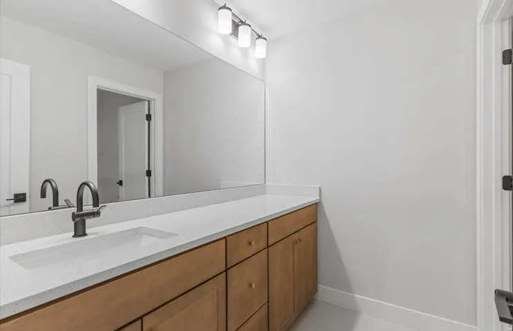 Expansive vanity with light wood-finish cabinetry, a single integrated sink, and a dark bronze-finish faucet