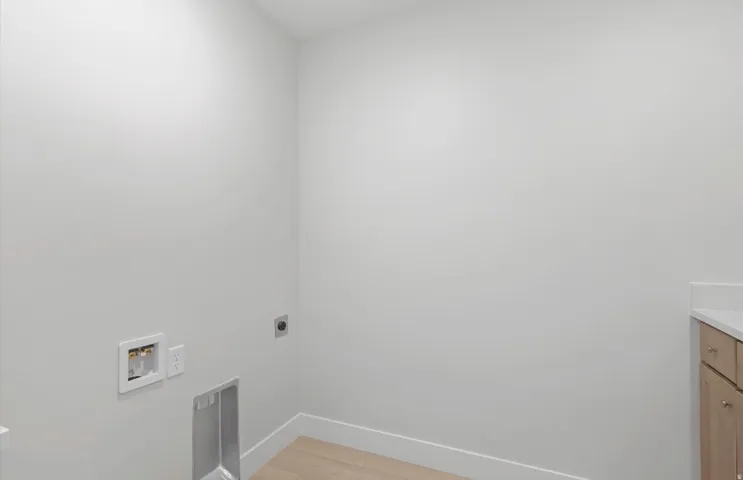 Dedicated utility space featuring light wood-finish flooring, light-toned walls, and a built-in counter with cabinetry