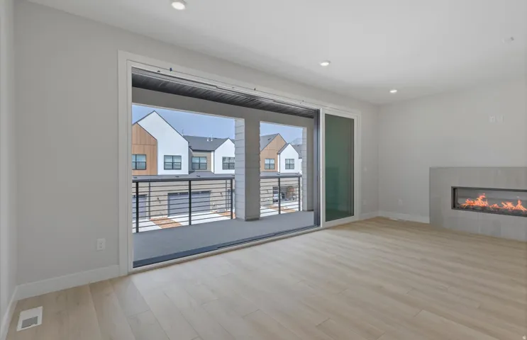 Light wood-finish flooring, recessed lighting, and a modern linear fireplace with a tile surround