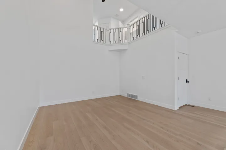 Expansive open-concept room featuring wood-finish flooring, a contemporary black metal railing, and recessed lighting