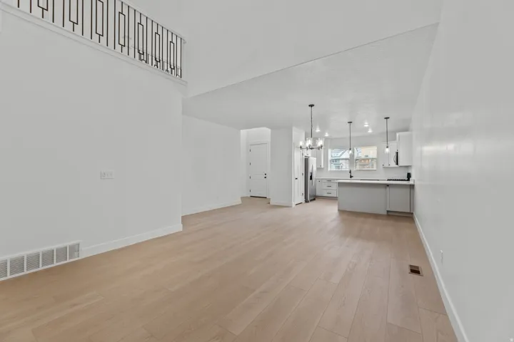 Wood-finish flooring, white walls, and a contemporary kitchen with a gray island and stainless steel appliances