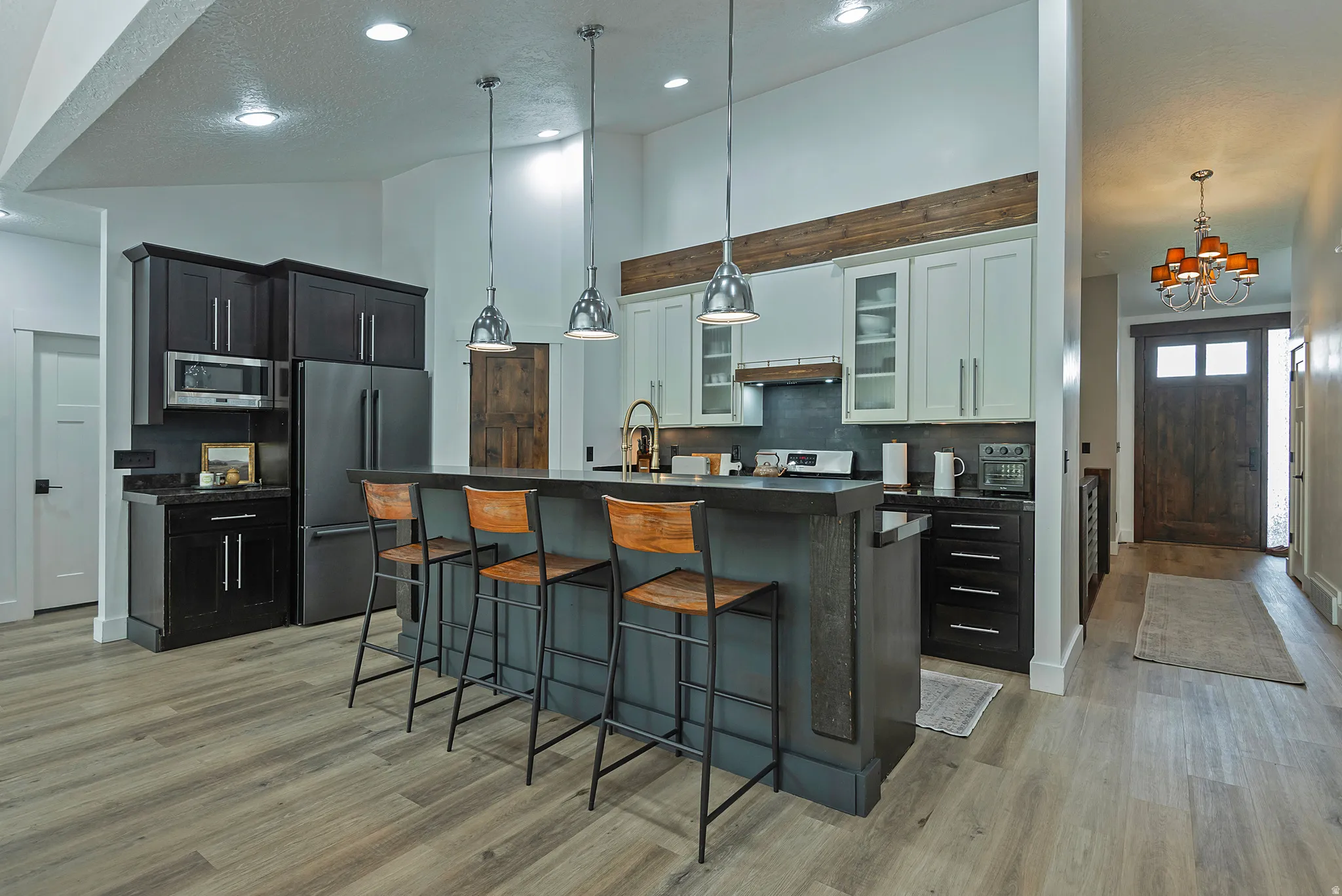 Chef's kitchen featuring dual stainless steel appliances, gray quartz countertops, and a large center island with seating