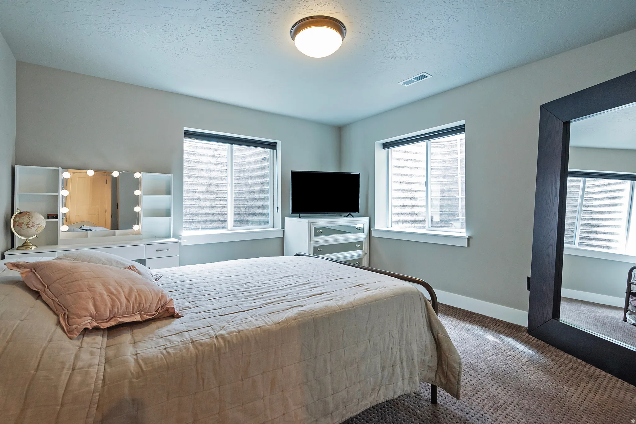 Warm wall color, dual windows with blinds, recessed ceiling light, and wall-to-wall carpeting
