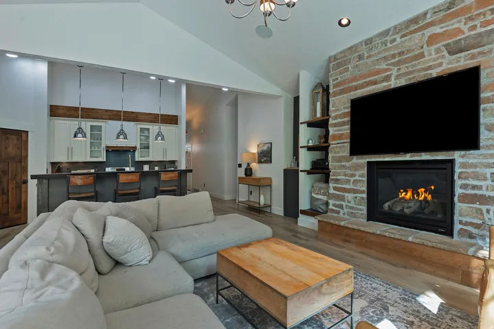 Open-concept living space anchored by a linear gas fireplace with exposed brick surround and integrated shelving