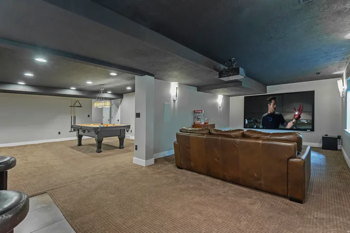 Expansive recreation room featuring engineered wood-finish flooring, recessed ceiling lighting, and a wood-finish bar with integrated storage