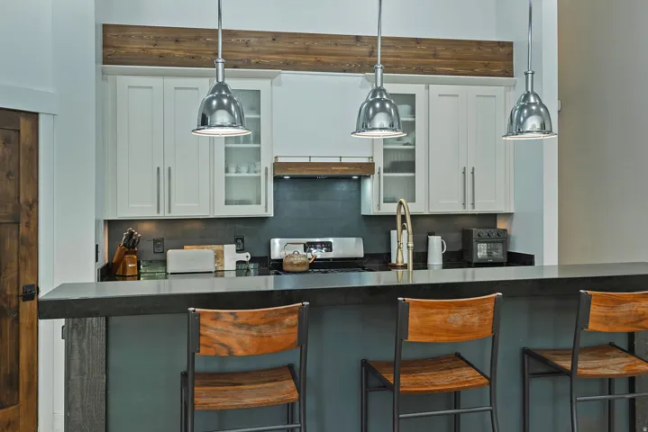 Kitchen featuring a dark countertop, white upper cabinetry, and three pendant lights