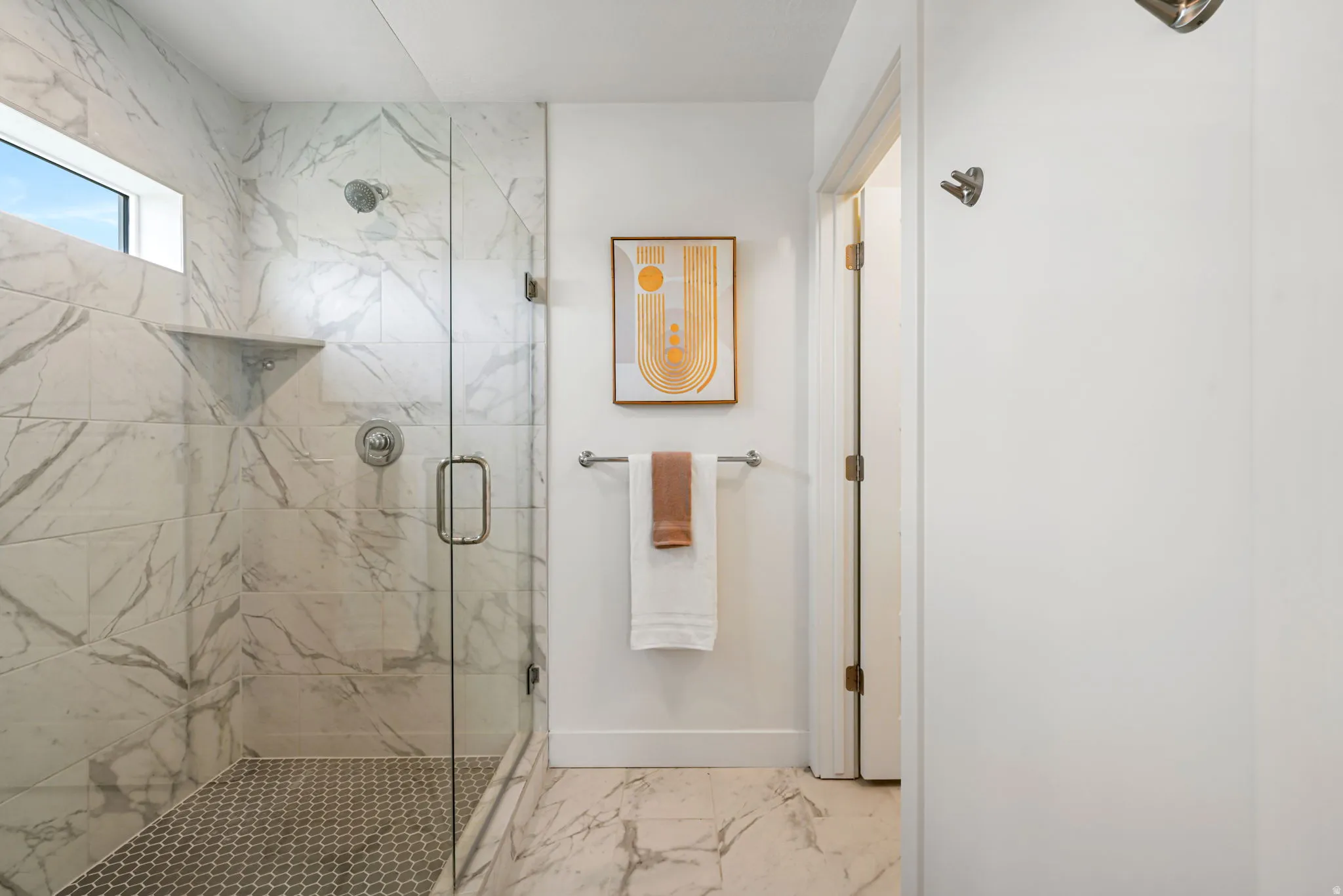 Walk-in shower with clear glass enclosure and hexagon tile floor