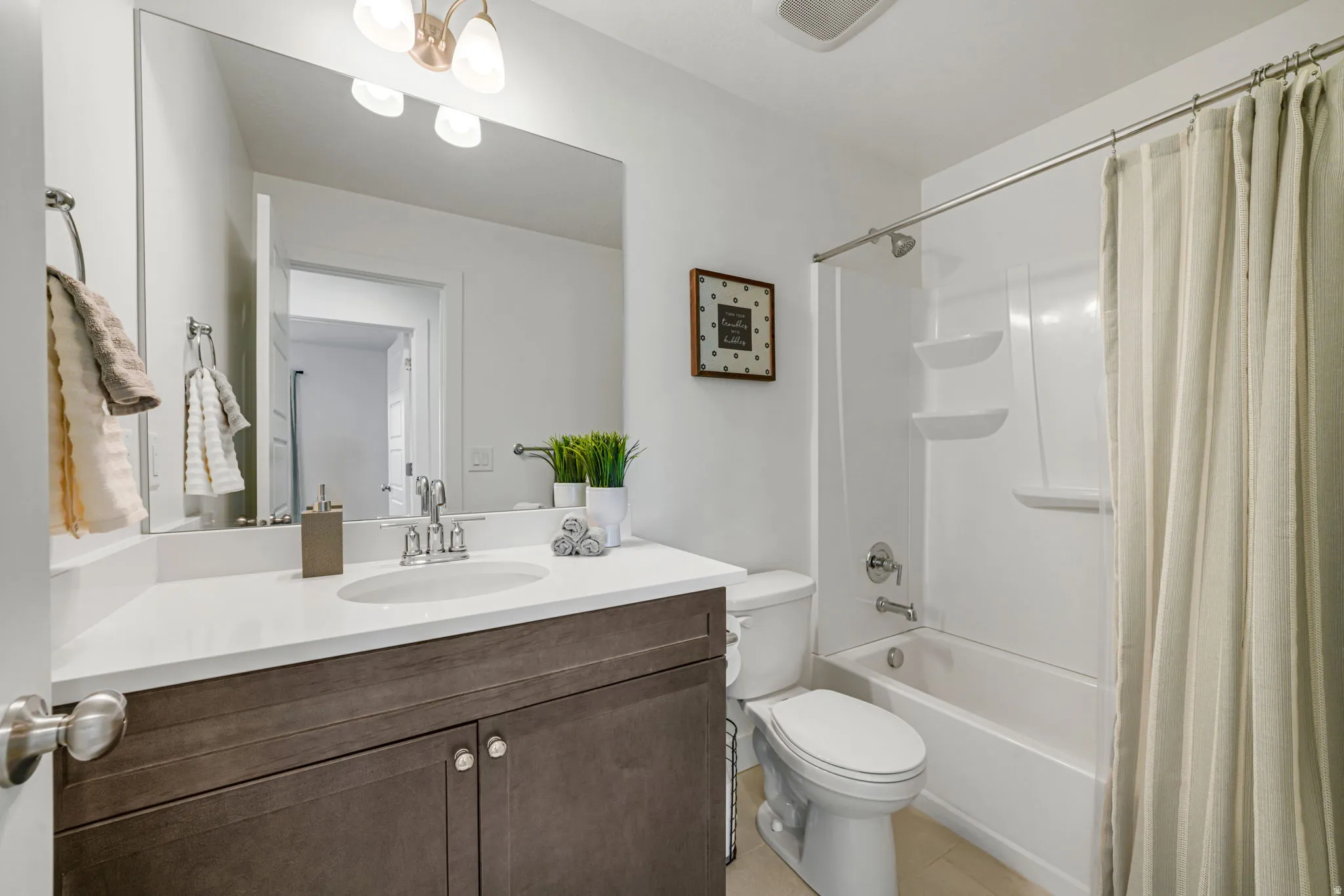 Spa-inspired bathroom featuring a dark wood-finish vanity with dual handles, white quartz countertop, and chrome faucet