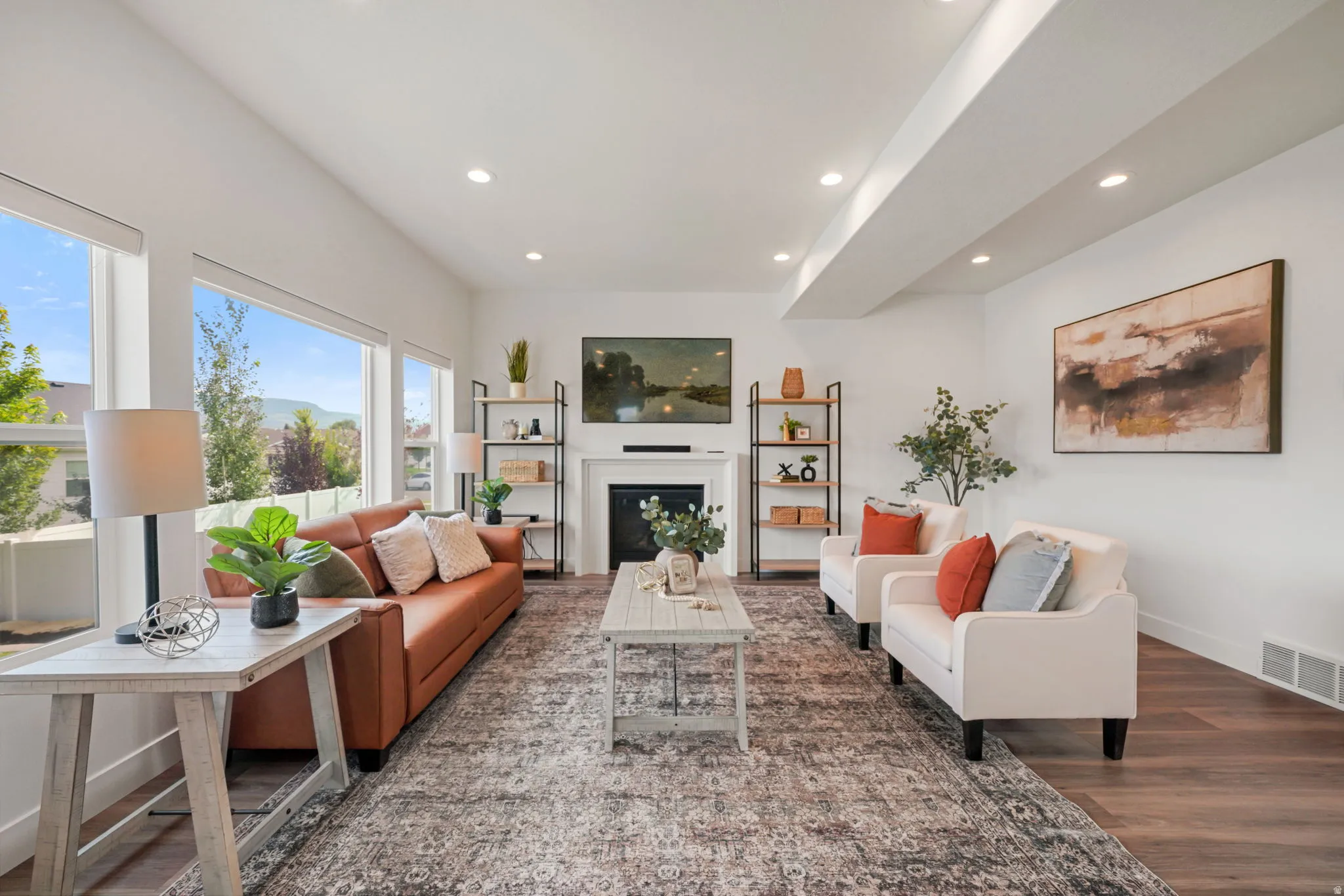Spacious living area featuring large windows, wood-finish flooring, a contemporary fireplace, recessed lighting, and built-in shelving